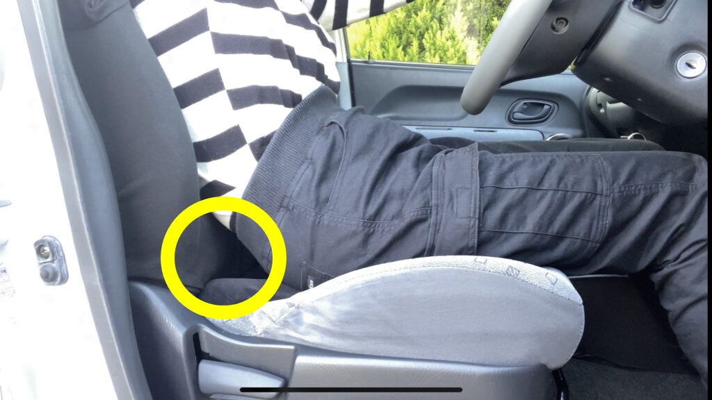 運転席のシートの浅く腰掛けて三角部分ができている人